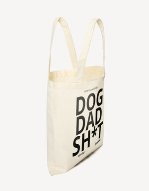 Off-white canvas tote bag with the words "DOG DAD SH*T - EST 2021 -" and "EMPAWR" logo, shown from the side.
