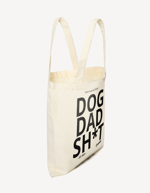 Off-white canvas tote bag with the words "DOG DAD SH*T - EST 2021 -" and "EMPAWR" logo, shown from the side.
