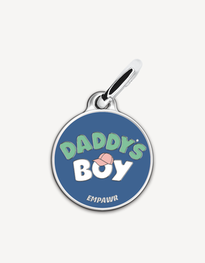 Empawr charm with the phrase "Daddy's Boy" in white letters on a blue background, with a pink baseball cap graphic and silver trim. The brand name "EMPAWR" is at the bottom.