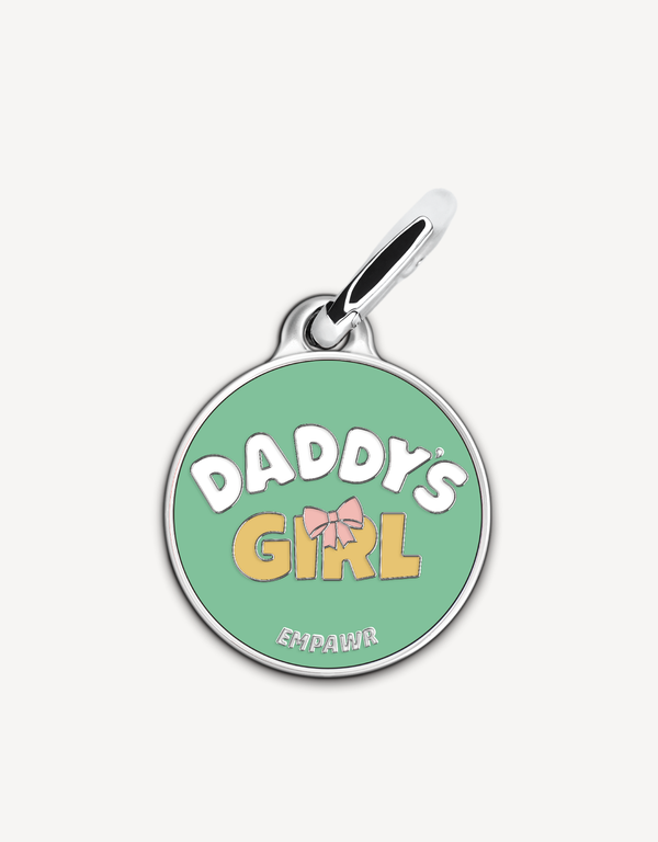 Empawr charm with the phrase "Daddy's Girl" in yellow letters on a green background, with a pink bow and silver trim. The brand name "EMPAWR" is at the bottom.