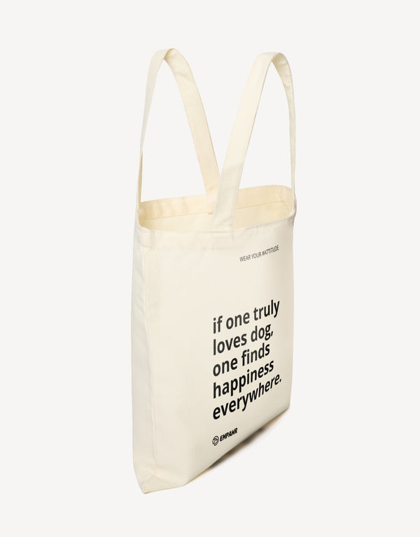 Off-white canvas tote bag with the quote "if one truly loves dog, one finds happiness everywhere" by Empawr, shown from the side.
