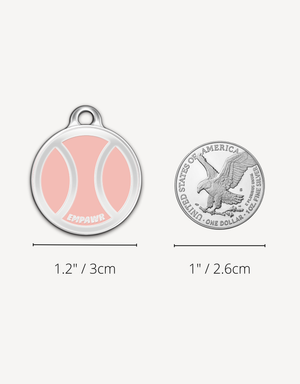 Empawr pink tennis ball charm next to a US dollar coin for size comparison. The charm is 1.2 inches (3 cm) in diameter, and the coin is 1 inch (2.6 cm).