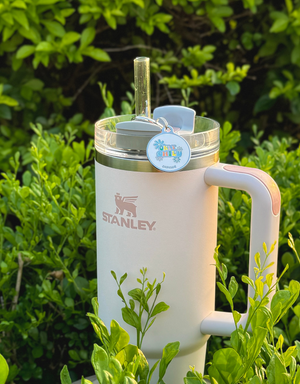 Round floral "Only Child" pet tag attached to a light-colored Stanley tumbler with a clear straw.